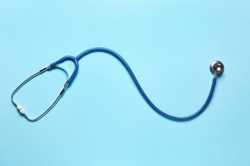 Modern stethoscope on color background