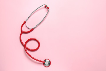 Modern stethoscope on color background