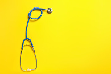 Modern stethoscope on color background