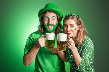 Young couple with beer on color background. St. Patrick's Day celebration