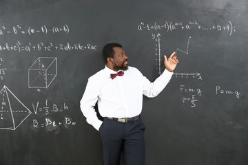 African-American math teacher near blackboard in classroom