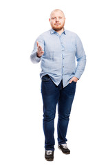 Smiling red-haired young man with a beard in a blue shirt and full-length jeans. Isolated over white background. Vertical.