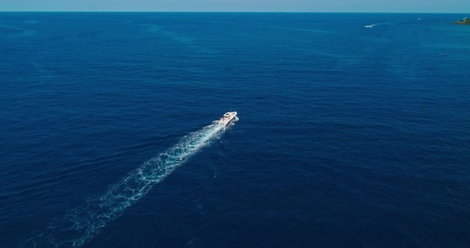 Aerial following, rotating over trolling island fishing boat, Roatan