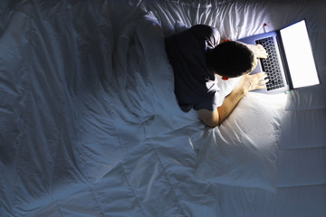 Man in bed with laptop using internet in online service - obrazy, fototapety, plakaty