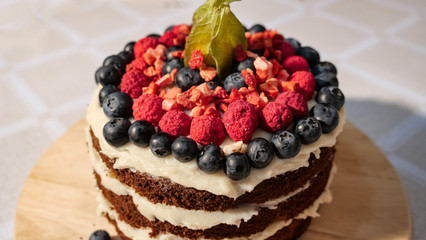 cake is decorated with fresh strawberries and blueberries on the table. Close up.