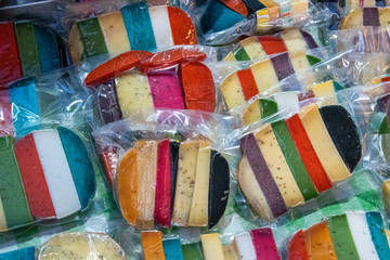 Brightly coloured favored cheese wrapped for sale at a market.