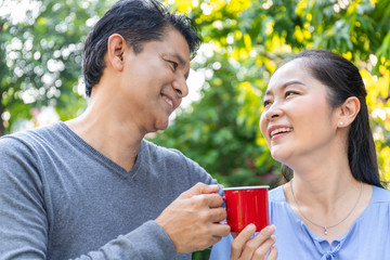 Senior Asian couple drinking coffee at the garden.