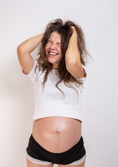 Naklejka premium The young beautiful pregnant woman experiences strong emotions on a white background