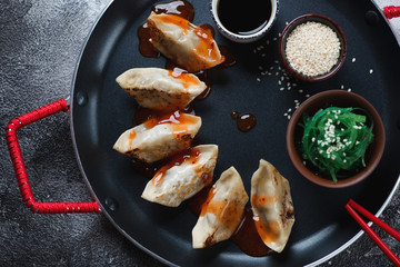 Close-up of pan fried gyoza dumplings with seaweed salad, sesame and soy sauce, view from above
