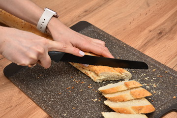 French Baguette on cut board. Fresh bread on the kitchen table. The healthy eating and traditional bakery concept.