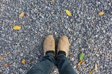 Feet with shoes on the pebble stones