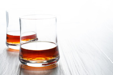 Whiskey or cognac or brandy in a glass glass on a white wooden background. Copy space