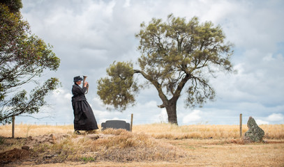 Woman in black dress playing trumpet in the cemetery