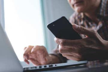 Man using mobile phone, working on laptop computer