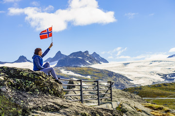 Tourist with norwegian flag in mountains