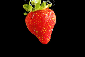 Strawberry falling into water at black background