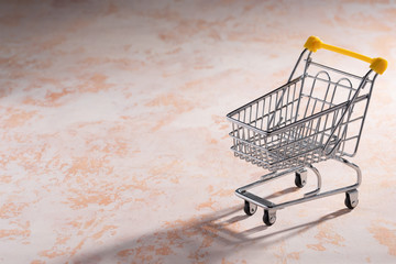 Shopaholic. Buyer. Shopping concept. Close-up. An isolated trolley and shopping basket on a peach...