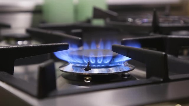 Close view of single gas burner on a stove cooktop, set to high flame.