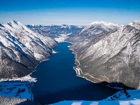Der Achensee in tiefem Blau liegt wie ein Fjord zwischen den Bergen des Karwendelgebirges und des Rofangebirges im Winter bei blauem Himmel