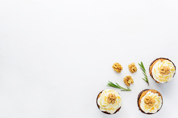 Cupcakes with cream cheese, walnut and rosemary on a white table. Horizontal orientation, copy space.