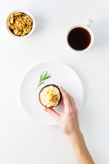 Carrot cupcake with cream, walnut, rosemary and a cup of coffee on a white table. A man takes a cupcake with his hand.