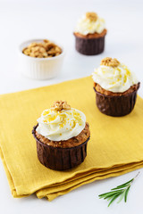 Cupcakes with cream, walnut and rosemary on a yellow napkin.