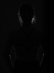 Schwarz-weiß Umrisse des Körpers einer Frau mit Haaren im Dunkeln und Hintergrundbeleuchtung