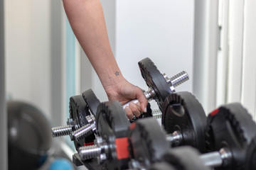 Fototapeta na wymiar Ein Arm greift nach der kurzen Hantel im Fitnessstudio