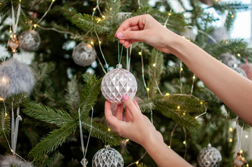 girl hangs Christmas decoration on the Christmas tree