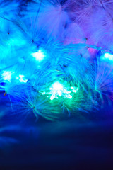 Obraz na płótnie Canvas A fragment of a luminous multi-colored Christmas garland and natural fluff on a black background