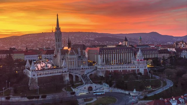 Budapest, Hungary - 4K moving time-lapse (hyperlapse) footage of drone flying by Fisherman's Bastion (Halaszbastya) and Matthias Church at dusk when lights turned on with a beautiful golden sunset sky