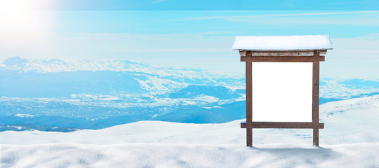 Blank wooden billboard, signpost in front of a mountain landscape with snow. Isolated surface for mockup. Copy space beside