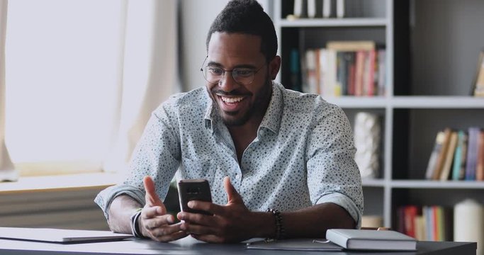 Excited african guy hold smartphone amazed with mobile online win