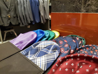 Colorful napkin for selection with different  pattern of suit blur as blackground inside men tailor made suit clothing store. Traditional and luxury formal cloth for male.