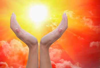 Fototapeta na wymiar Female hands around the sun in a cloudy sky