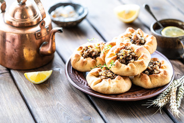 Group of individual pies with meat and potato - vak balish. Tatar traditional pies. Wooden background.