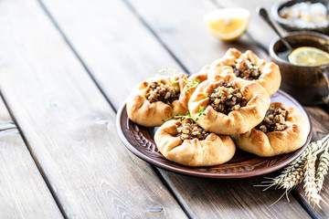 Group of individual pies with meat and potato - vak balish. Tatar traditional pies. Wooden background. Copy space