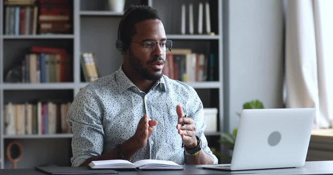 Serious african businessman wear headset conference calling by webcam