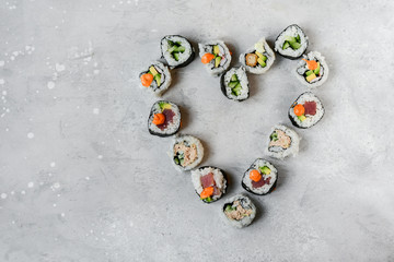 Set sushi roll in the shape of a heart on a stone table. Valentine's day romantic menu, dinner lovers. banner food delivery Valentine's day. Top view of assorted sushi, uramaki, hosomaki and nigiri.