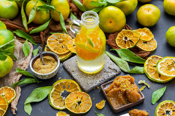 Fototapeta na wymiar Organic fresh tangerine water in a glass bottle surrounded by dehydrated mandarines. Vegan drink. Fresh fruit water in a bottle glass