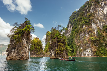 Naklejka na ściany i meble Longtail boat passing by beautiful limestone cliffs in Khao Sok National Park