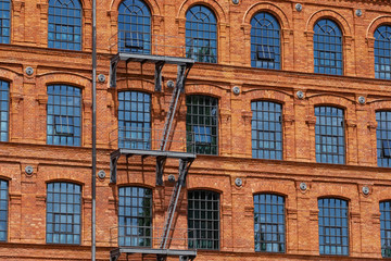 Fototapeta na wymiar Red brick classic industrial building facade with multiple windows background. 