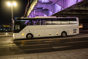 Tourist Bus Travels at Night on the Illuminated Road