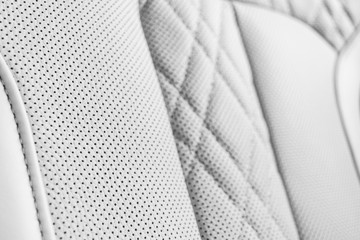 Modern luxury Car white leather interior. Part of perforated leather car seat details. White Perforated leather texture background. Texture, artificial leather with stitching. Perforated leather seats
