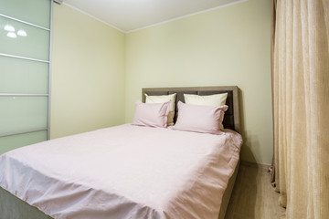 Double bed with pillows in interior of the modern intimate bedroom in loft flat in light color style apartments