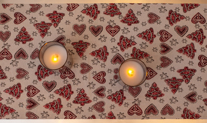 Top view of a tablecloth with Christmas pattern and candles on it