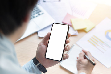 Mockup image blank white screen cell phone.man hand holding texting using mobile on desk at office.background empty space for advertise text.people contact marketing business,technology 