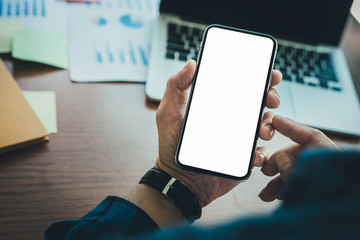 Mockup image blank white screen cell phone.man hand holding texting using mobile on desk at office.background empty space for advertise text.people contact marketing business,technology 