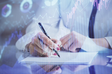 Double exposure of hands making notes with forex chart huds. Stock market concept.