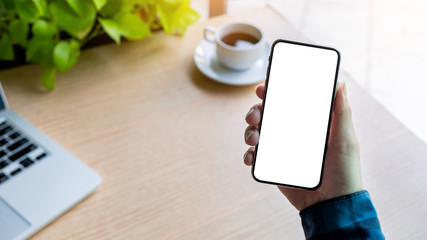 Mockup image blank white screen cell phone.man hand holding texting using mobile on desk at office.background empty space for advertise text.people contact marketing business,technology 